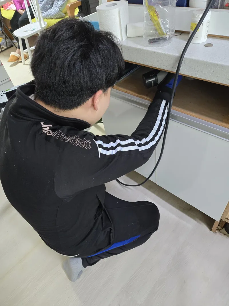 공구를 두고 하부장 배관을 보수 중인 모습